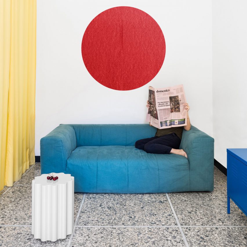 Living room with blue sofa, yellow curtain and red circular wall hanging