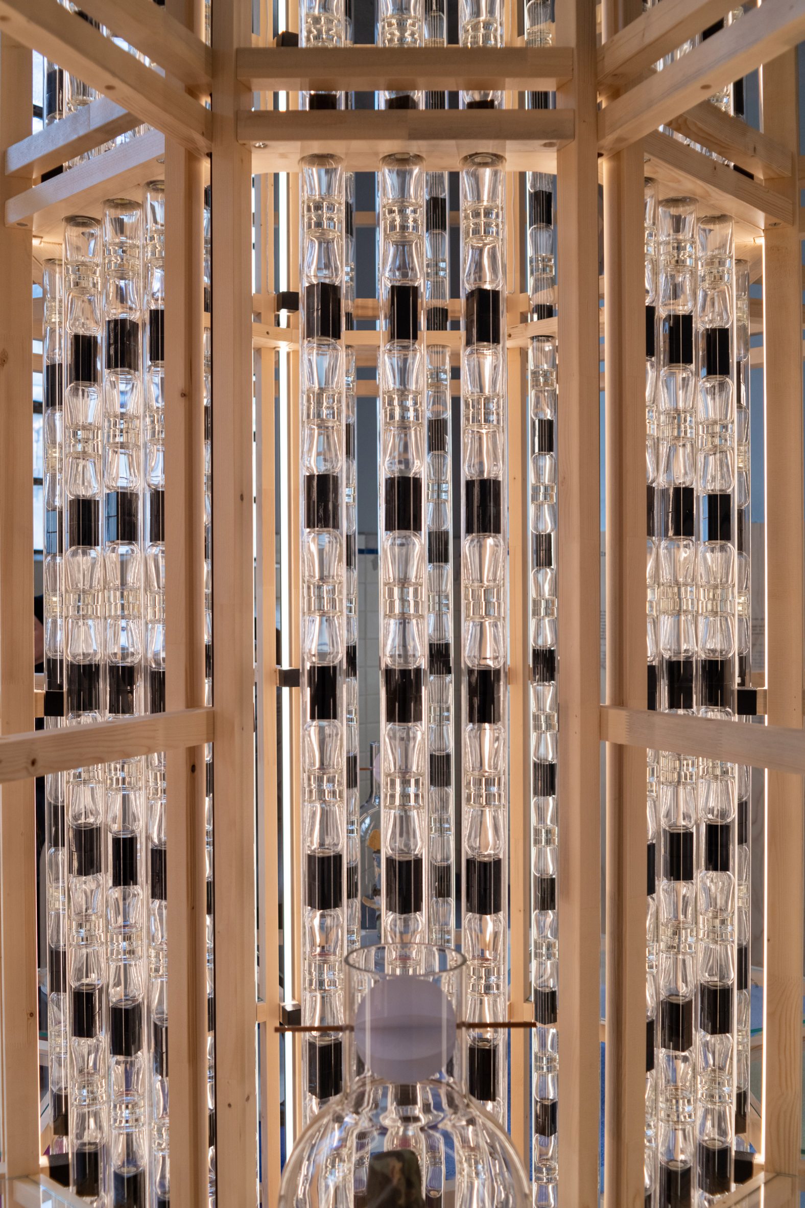 Perfume bottles stacked inside transparent tubes in Les Eaux Primordiales installation