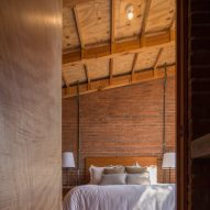 Bedroom with brick walls, wooden ceiling structure and a bed with white bedding