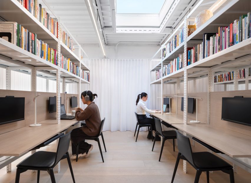Two rows of wooden desks with bookshelves above