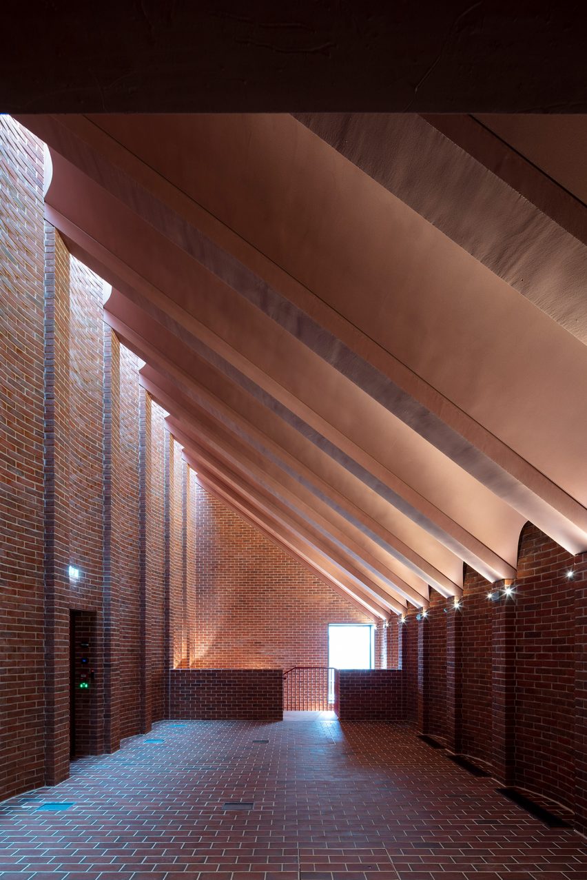 Interior of the International Rugby Experience building by Niall McLaughlin Architects with red-brick walls and slanted arched ceiling