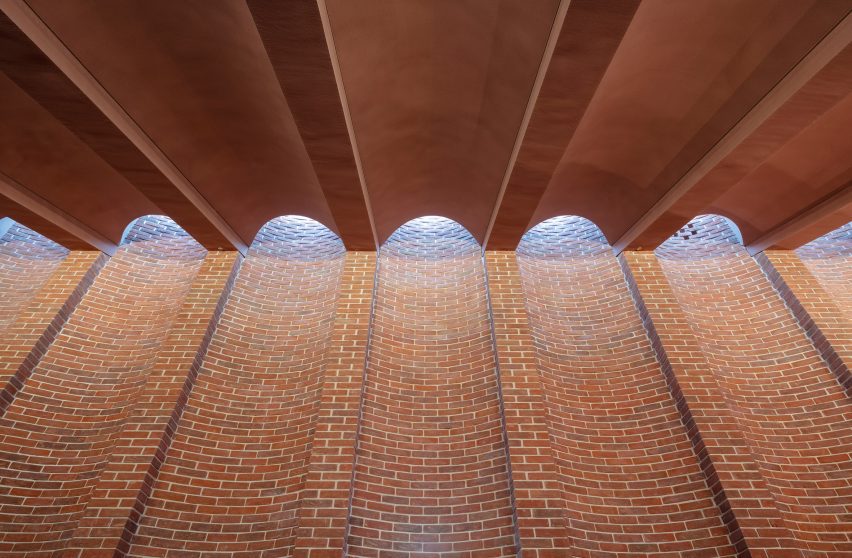 Red-brick wall with recessed bays aligning with arches in the ceiling