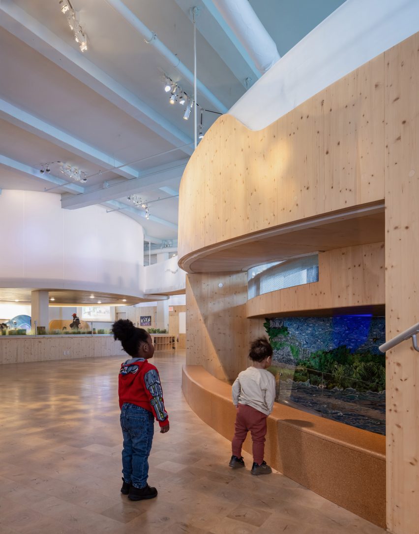 Museum interior with wood floors and children looking into a window display