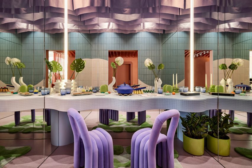 A small room with a dining table and two purple chairs, with mirrors on three sides