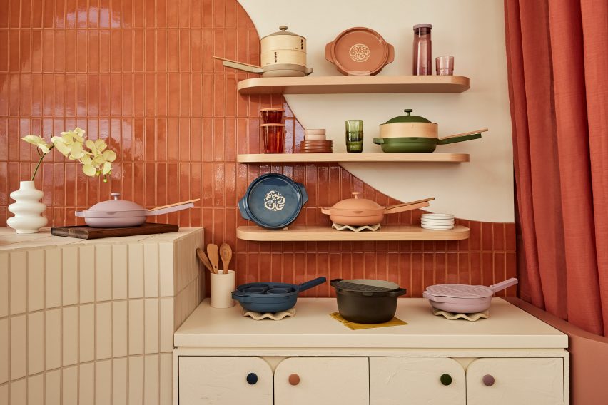 Cookware displayed on three shelves and cabinets below, against a tiled wall