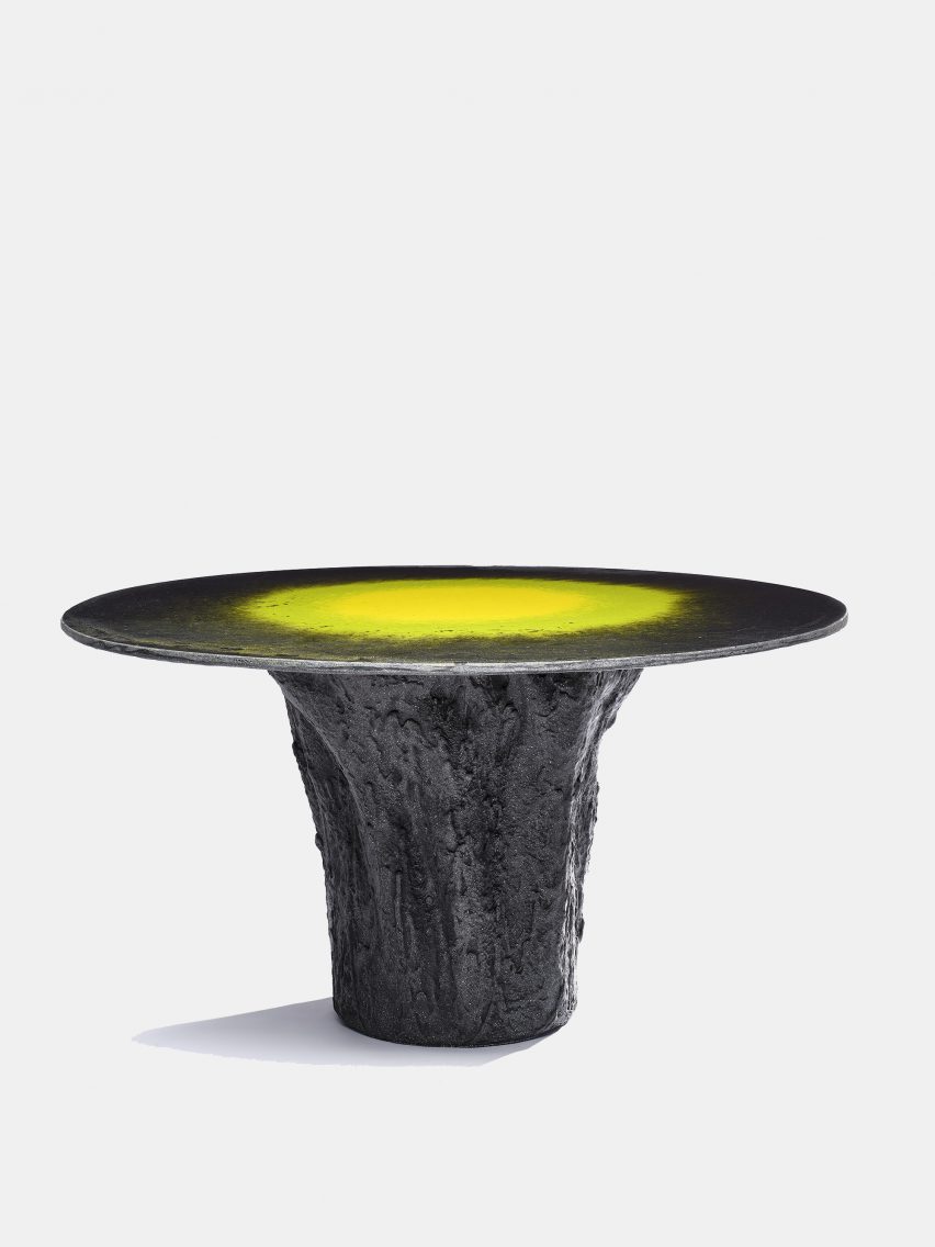 Photo of a round black table with a gnarled central base and a smooth top with concentric circles of yellow and green in the centre