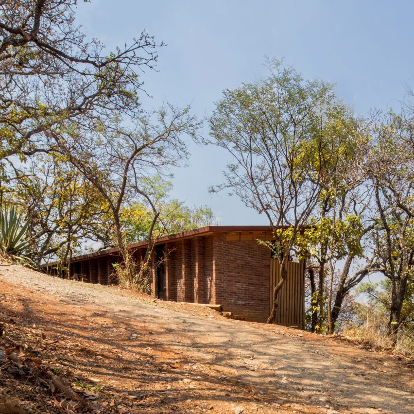 Wooden one-storey shed-like home on a sandy hill in Mexico with trees
