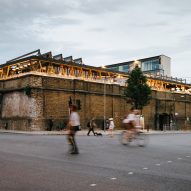 Wavy steel canopy shelters rooftop bar on historic stables in Camden