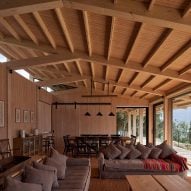 A living room in a timber-clad room with a pitched roof and grey sofas