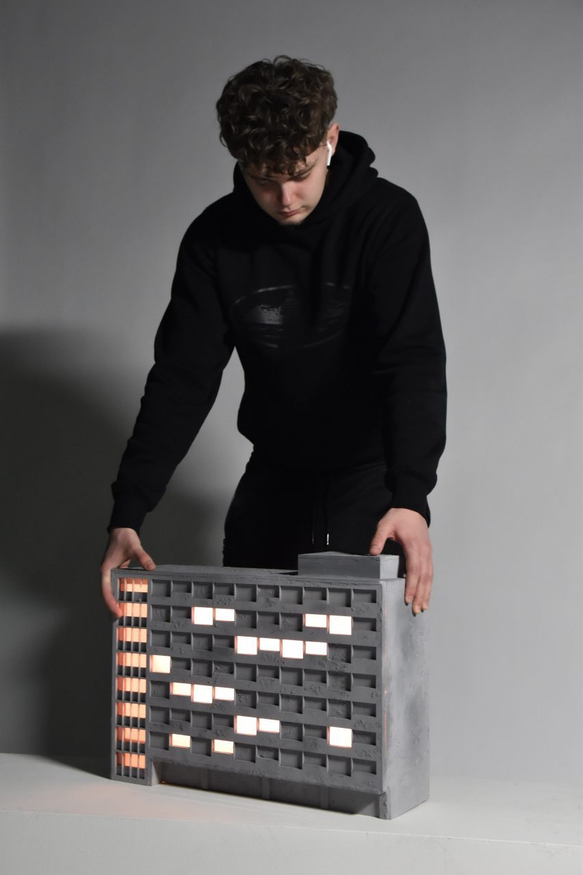 Student posing with building-lamp design on grey background