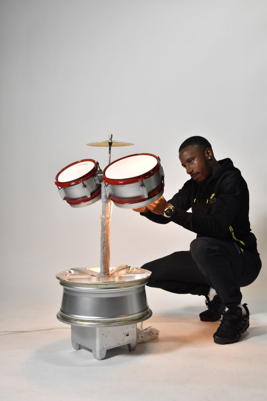 Student posing with sculptural lamp design on grey background