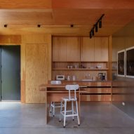Timber-clad kitchen interior with concrete floors and wooden storage