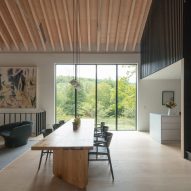 Open-plan dining and living space with timber floors, tall windows and exposed timber roof structure