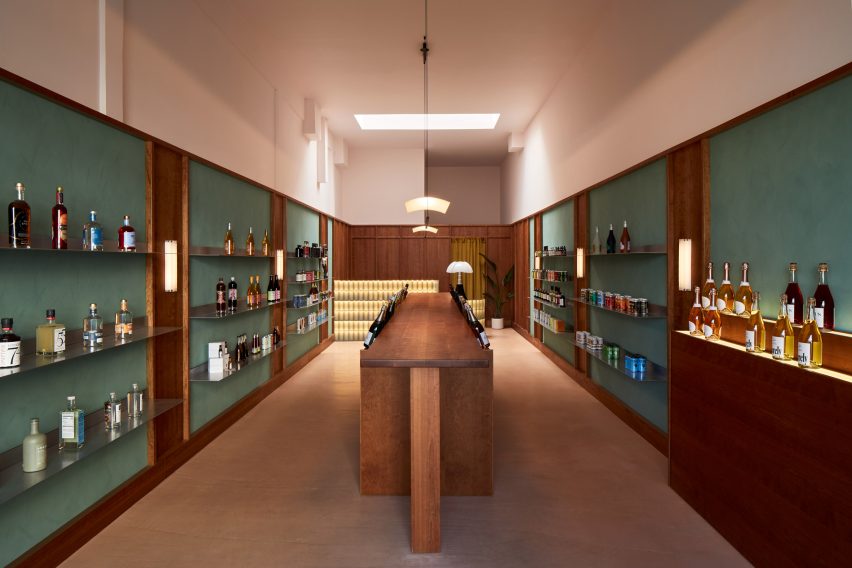 Tienda de botellas informada por Wes Anderson con mostrador central de madera y exhibidores a ambos lados 