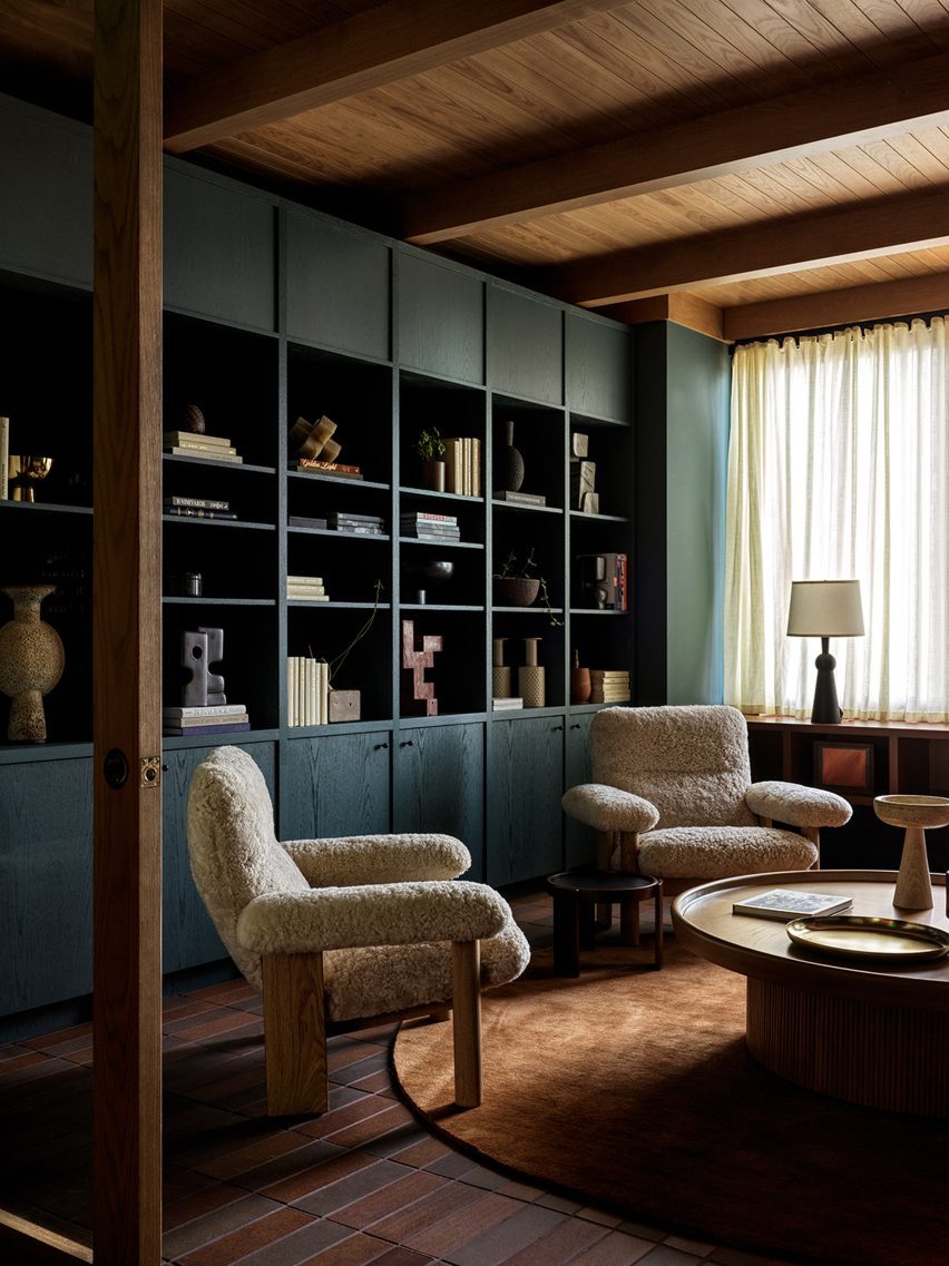 سالن استراحت با قفسه‌های کتاب آبی رنگ، دو صندلی راحتی و یک میز قهوه‌خوری
