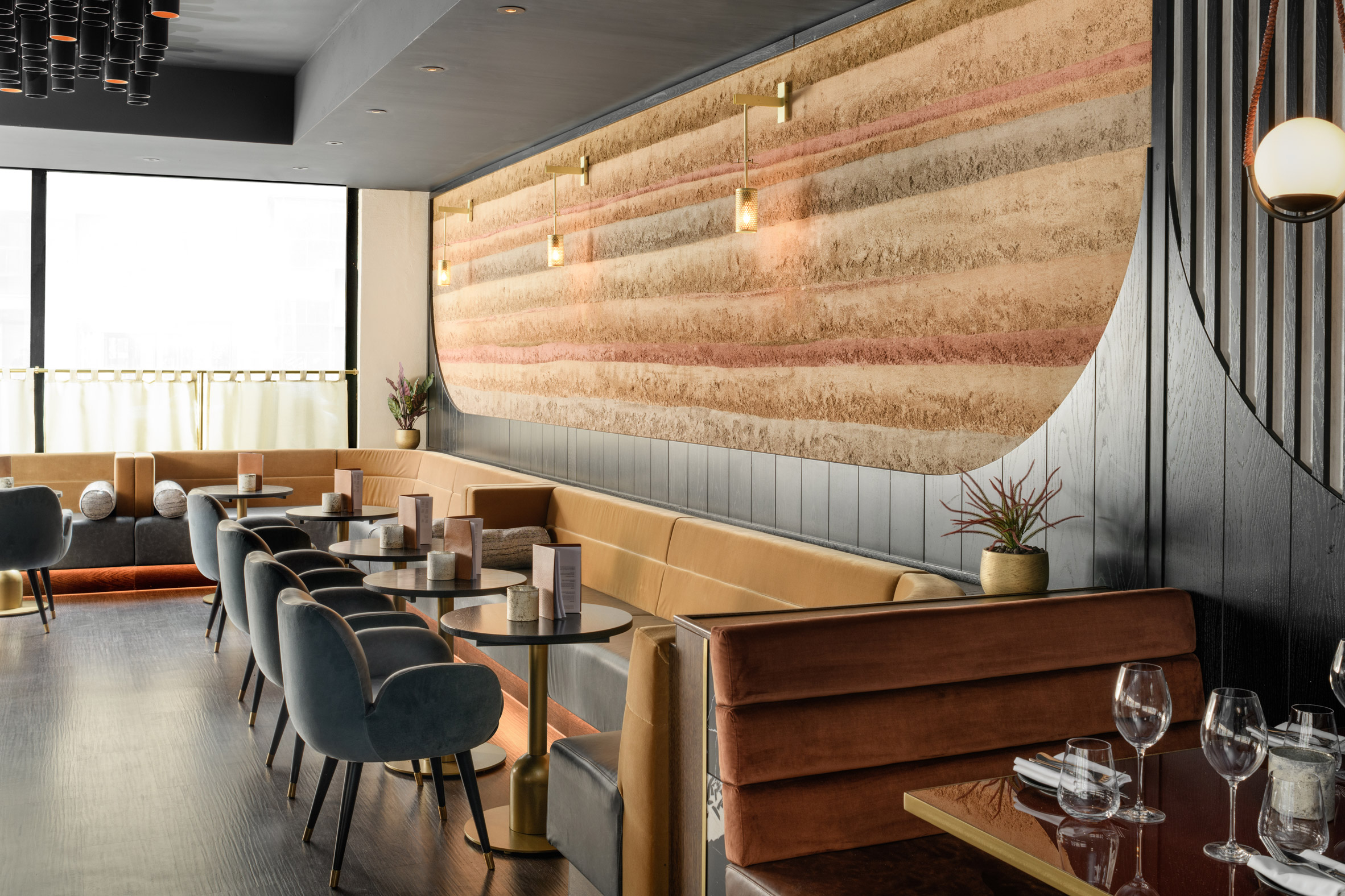 Restaurant interior with rammed earth wall and black chairs