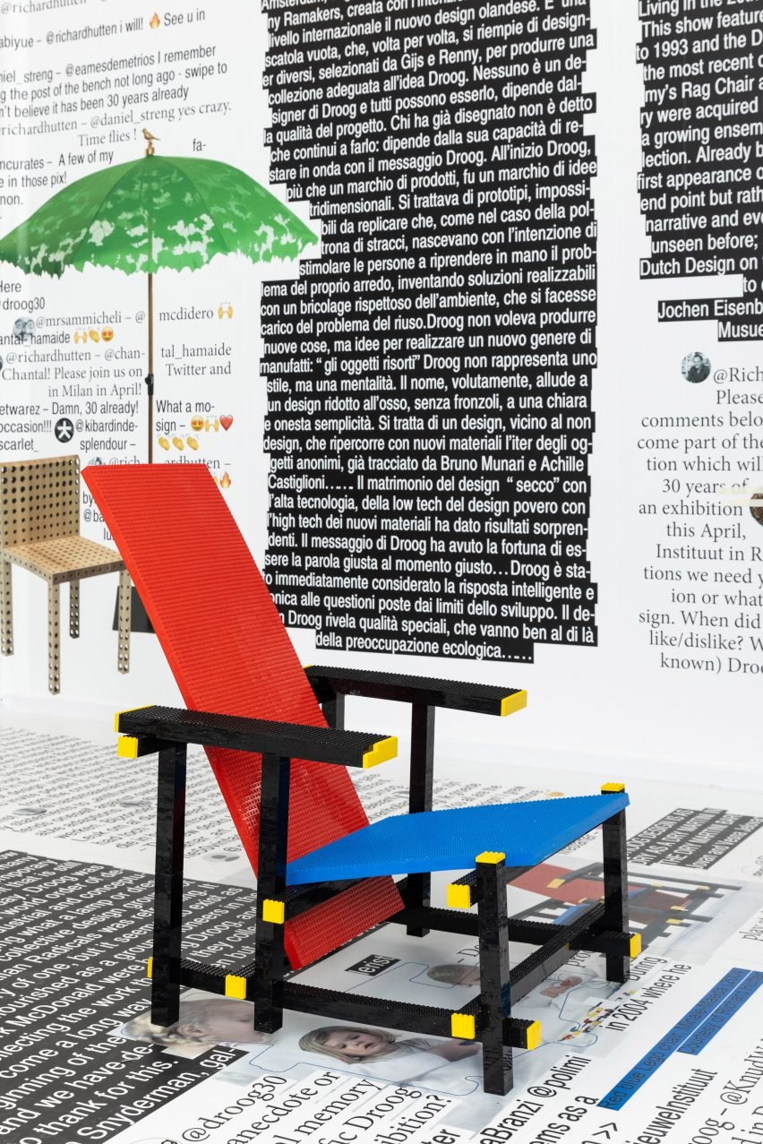 Photo of the Red and Blue Chair by Studio Minale-Maeda with printed-out sheets of text lining the walls and floor behind it