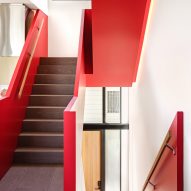 Staircase with dark wood stairs and red balustrades