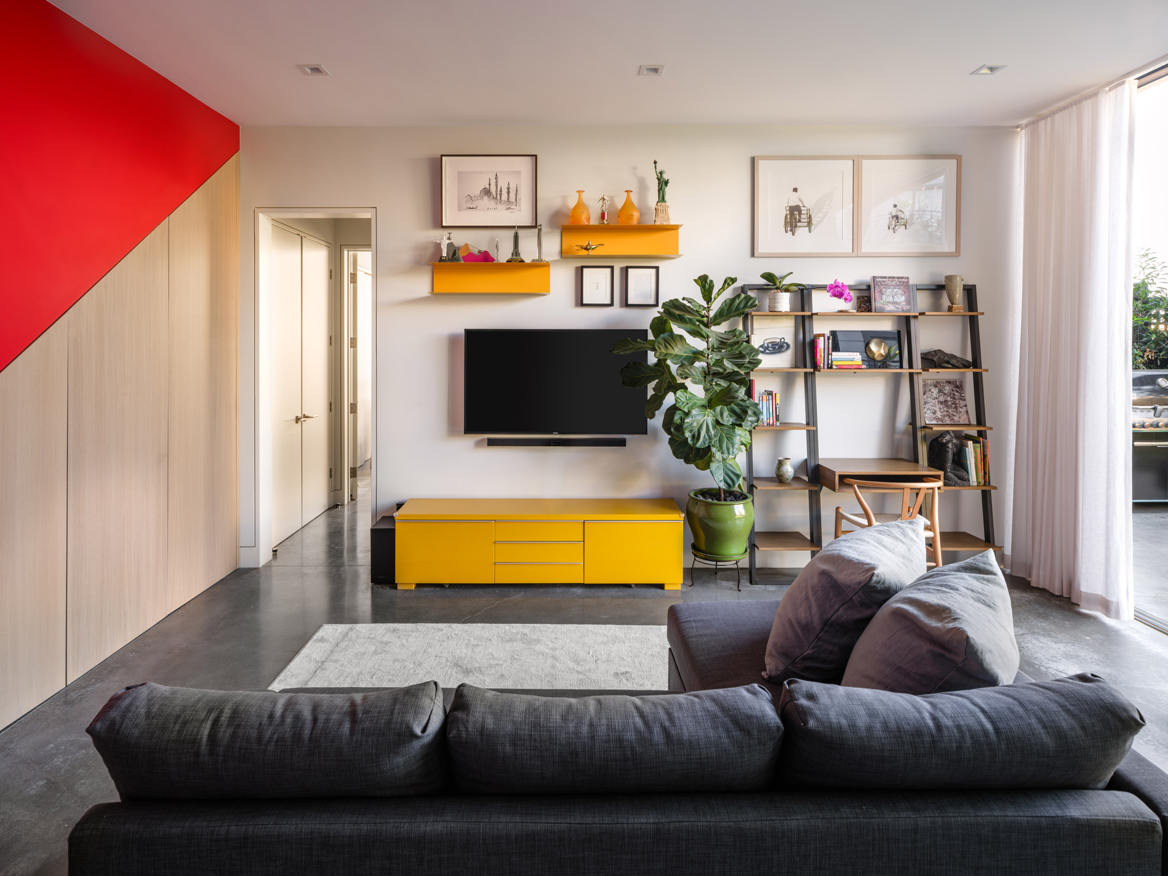 Living room at Red Stair House by Dumican Mosey with grey sofas and a red staircase
