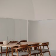 A white room with a wooden dining table and chairs
