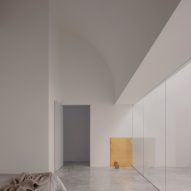 A bedroom with white walls, a curving ceiling and glass sliding door leading to a courtyard