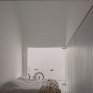 A white bedroom with a double bed and glass doors leading to an outdoor space with a bike