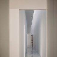 A white internal corridor with a skylight letting in sunlight