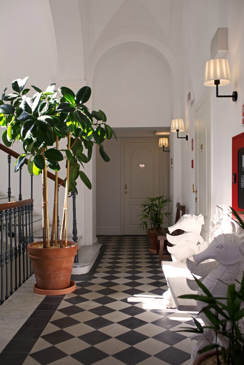 Hallway of Il Capri Hotel with checkerboard floor tiles and potted plant