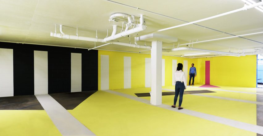 Large open venue space with a white, yellow and black graphic design on the walls and floor
