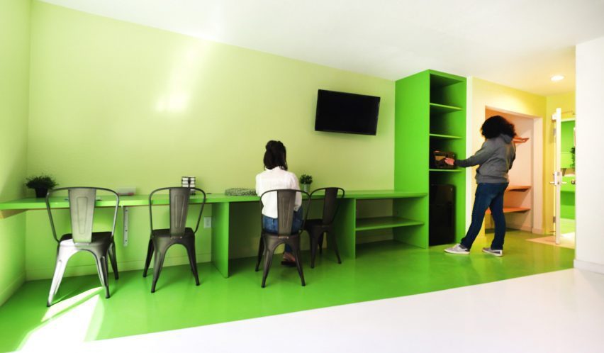 Зелено-белый интерьер с зелеными стеллажами вдоль стены и настенным телевизором