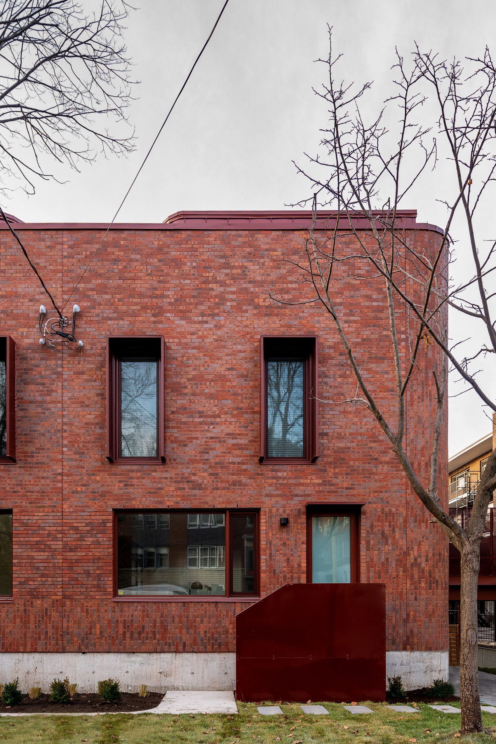 Curved brick facade with metal staircase and winter greenery