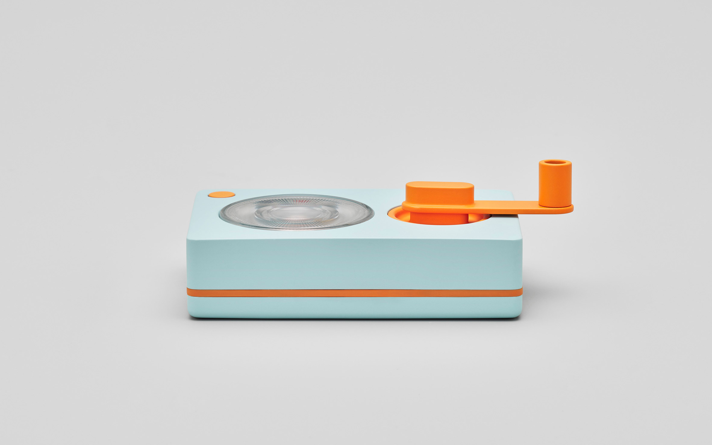 Photo of the Ambessa Play flashlight lying flat on its back, as seen from one side. An orange hand crank is attached to the front