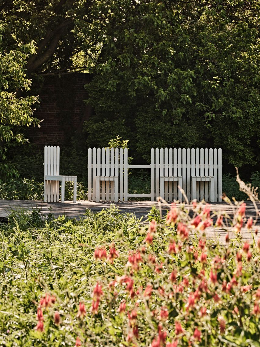 White picket fence bench with flowers in the foreground