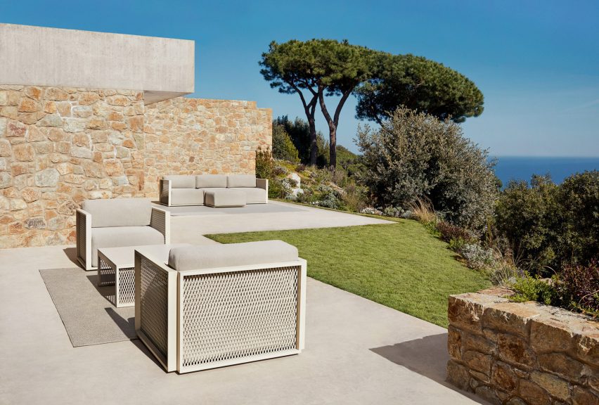 Metal furniture with soft cushions placed outside overlooking the sea