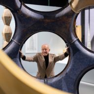 Norman Foster mirando a través de un agujero circular en una gran estructura escultórica en su exposición en el Centro Pompidou