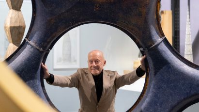 Norman Foster looking through a circular hole in a large sculptural structure at his exhibition in the Centre Pompidou