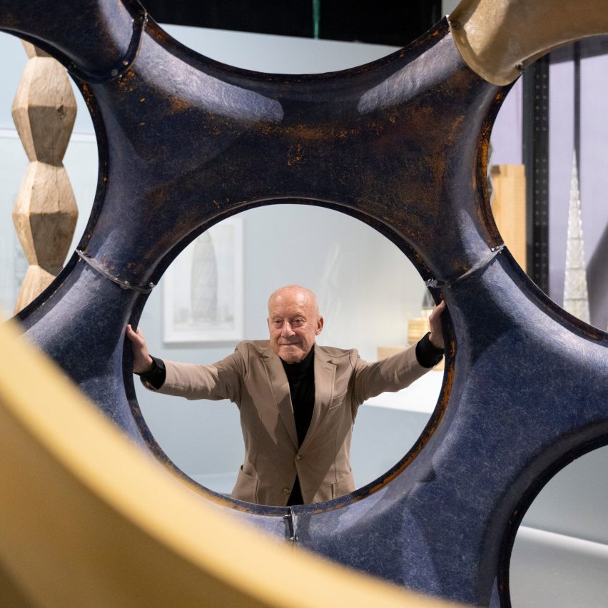 Norman Foster looking through a circular hole in a large sculptural structure at his exhibition in the Centre Pompidou