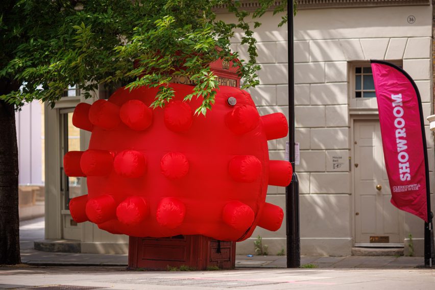 Red phone box covered with inflatable sculpture featuring protrusions