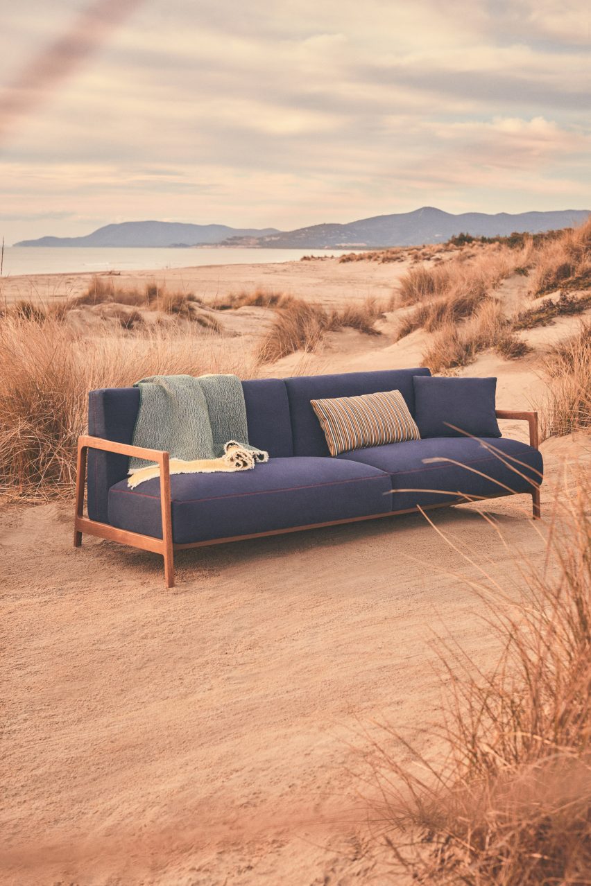 Un sofá azul marino situado en una playa.