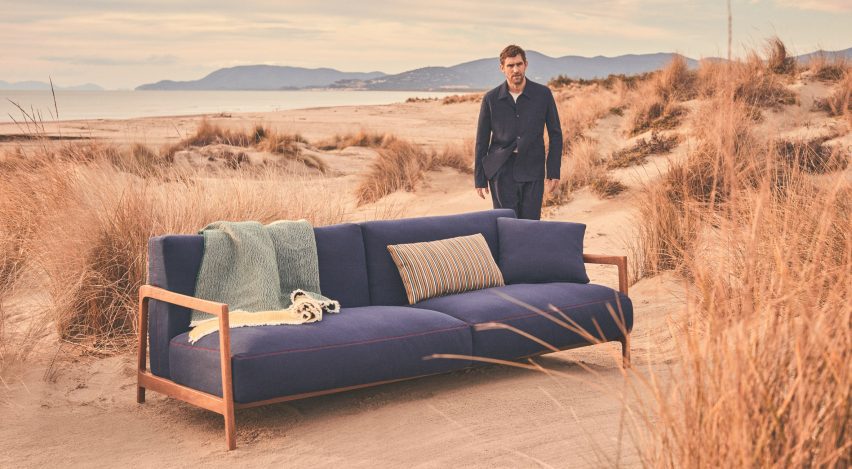 Man standing next to blue sofa on the beach