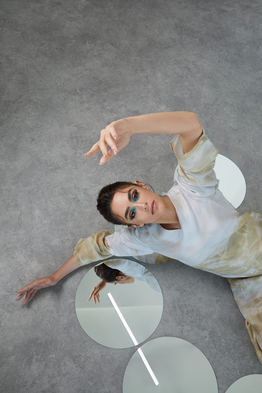 Model wearing neutral-coloured clothing next to four circular mirrors