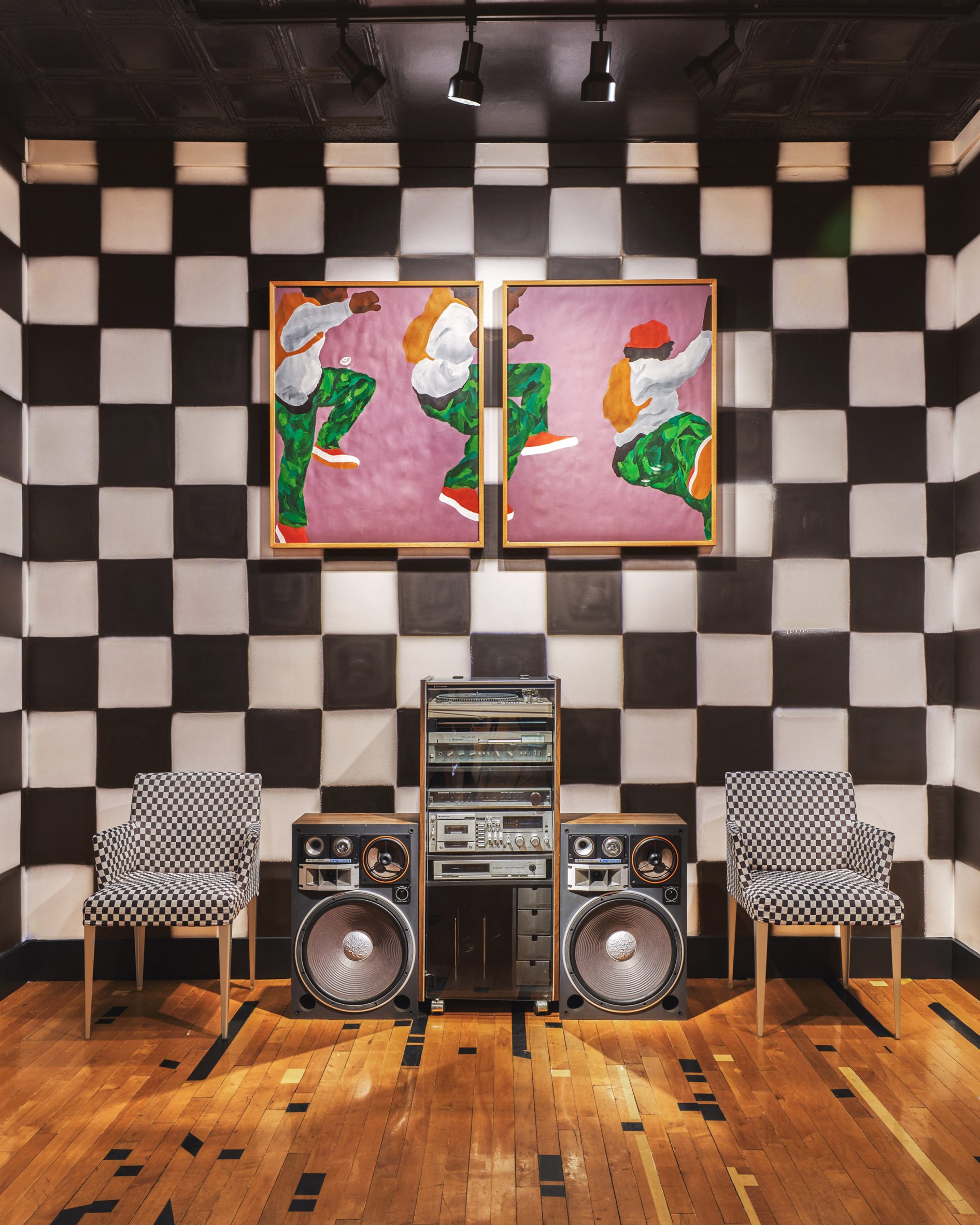 Checkerboard wall behind a stereo system and a pair of chairs