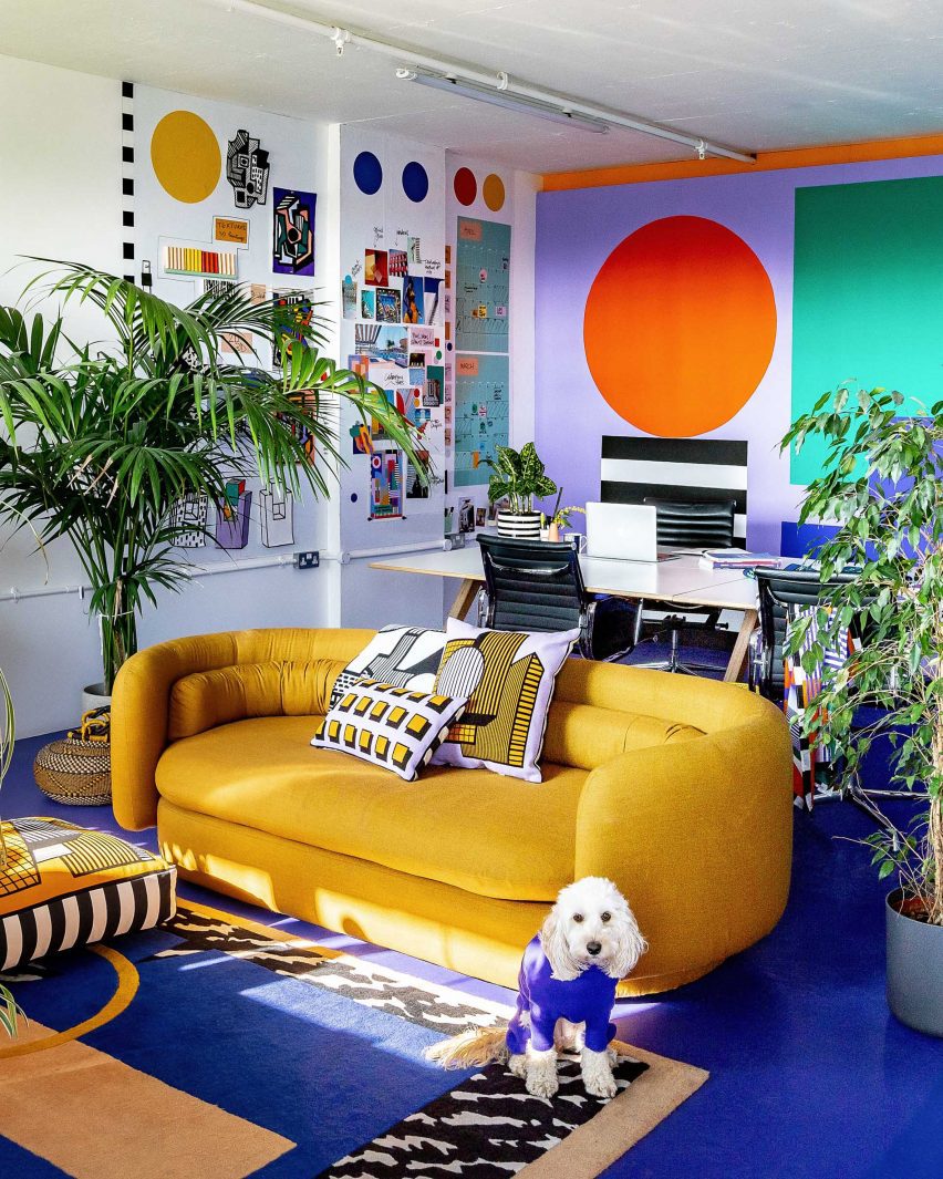 Foto de un colorido espacio de oficina con un sofá amarillo frente a una gran mesa de trabajo 