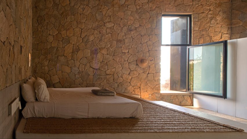 Bedroom with stone wall and bed on platform