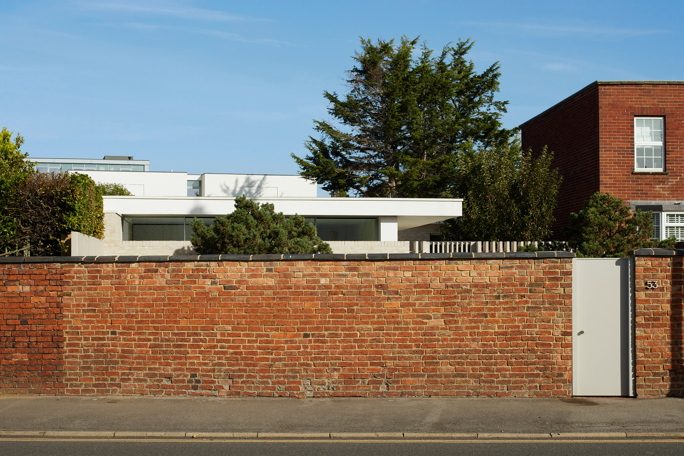 Brick wall concealing white house in Cheltenham