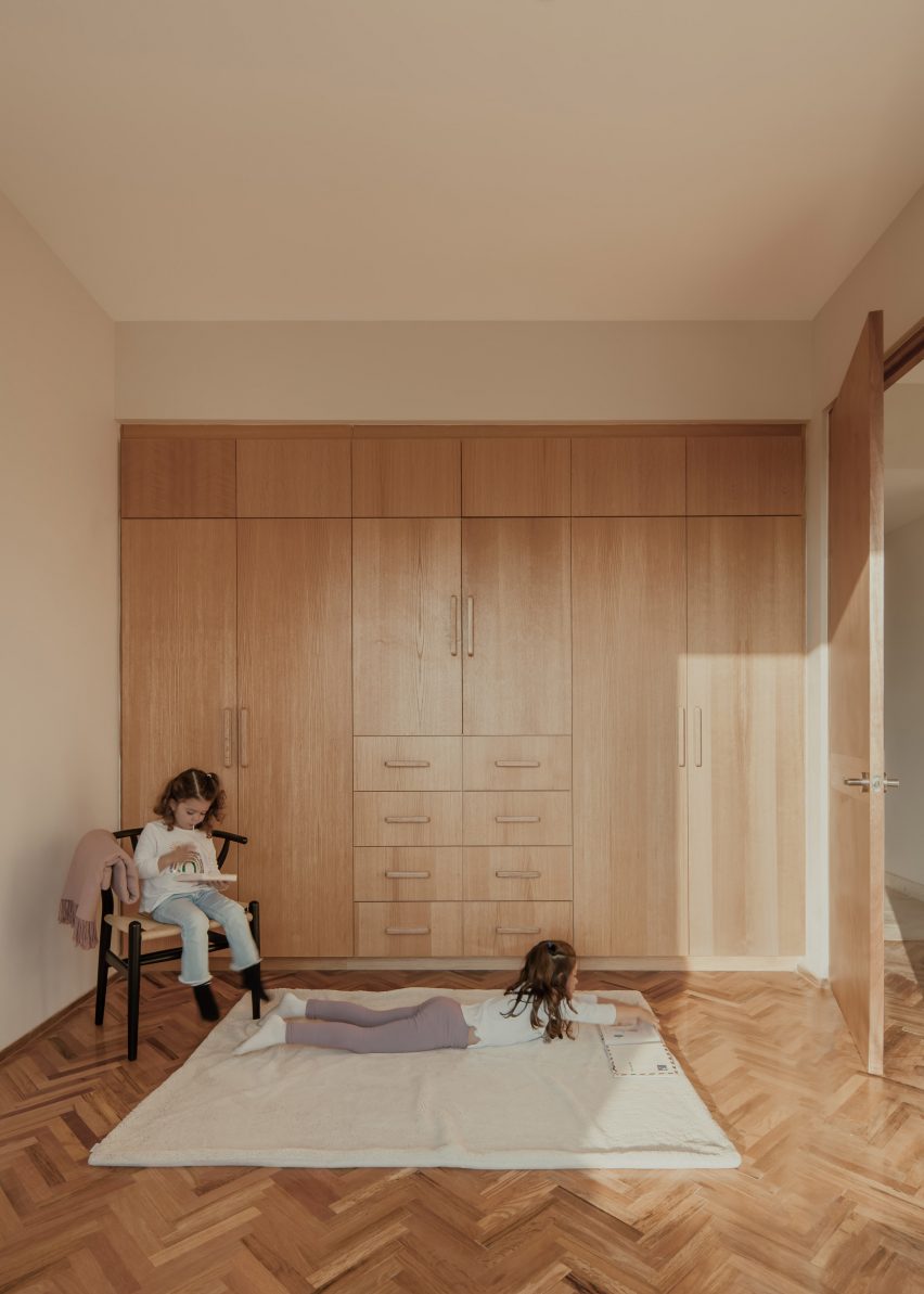 Внутренняя комната с белыми стенами, деревянным полом и встроенным деревянным настенным хранилищем