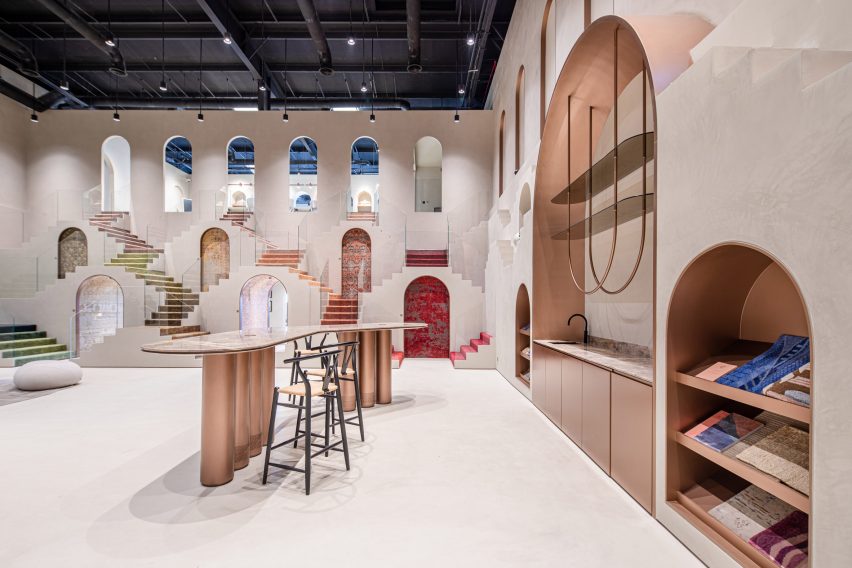 Foto de una sala de exhibición de doble altura en Dubái que muestra detalles en rosa metalizado en los muebles, las puertas, los huecos y los gabinetes