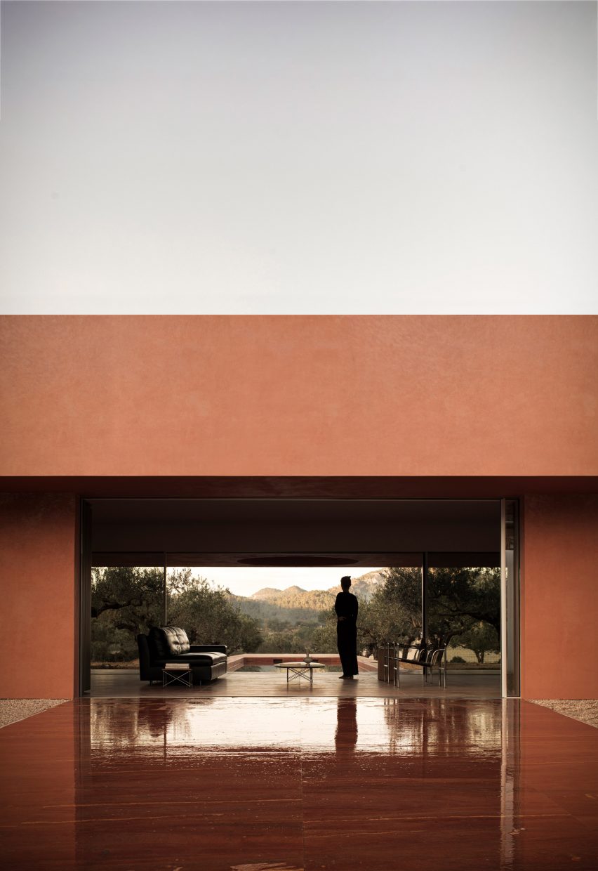 Person standing on opening of red-toned house in Spain