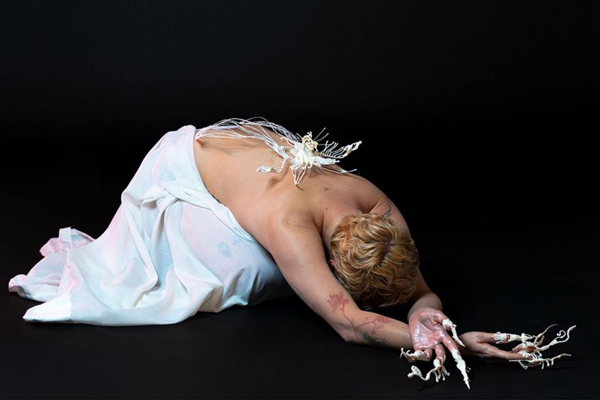 Modelo agachada con joyas blancas esqueléticas colocadas en la espalda y los dedos por estudiante de la Escuela de Arte y Diseño de Lucerna