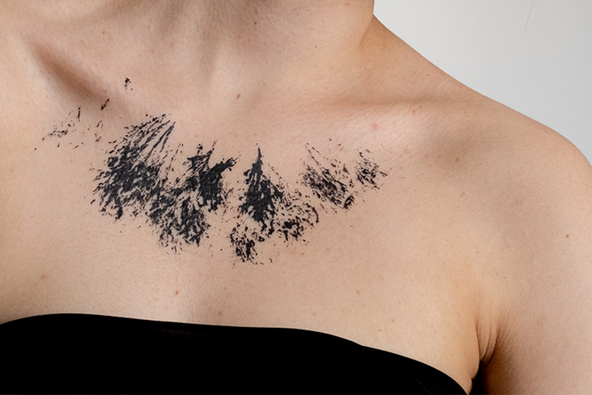 Black paint splatters painted on a person's chest
